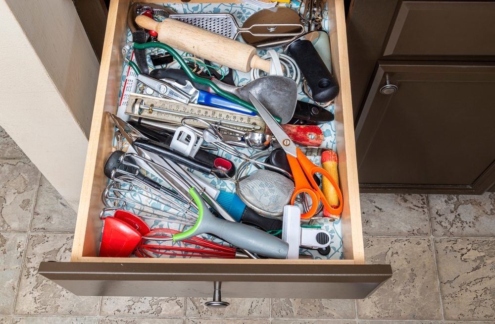 Where to start decluttering: one kitchen drawer Overstuffed kitchen drawer crammed with utensils including a rolling pin, grater, scissors, ladles and spatulas