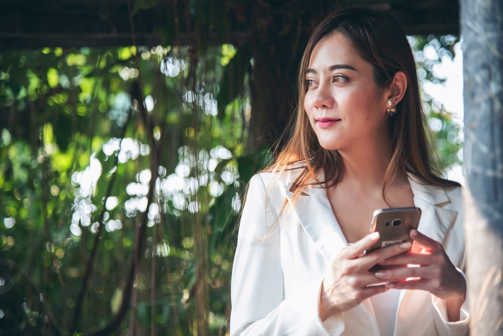 Employee taking a break outdoors and looking up from her phone, one small habit that helps prevent burnout at work