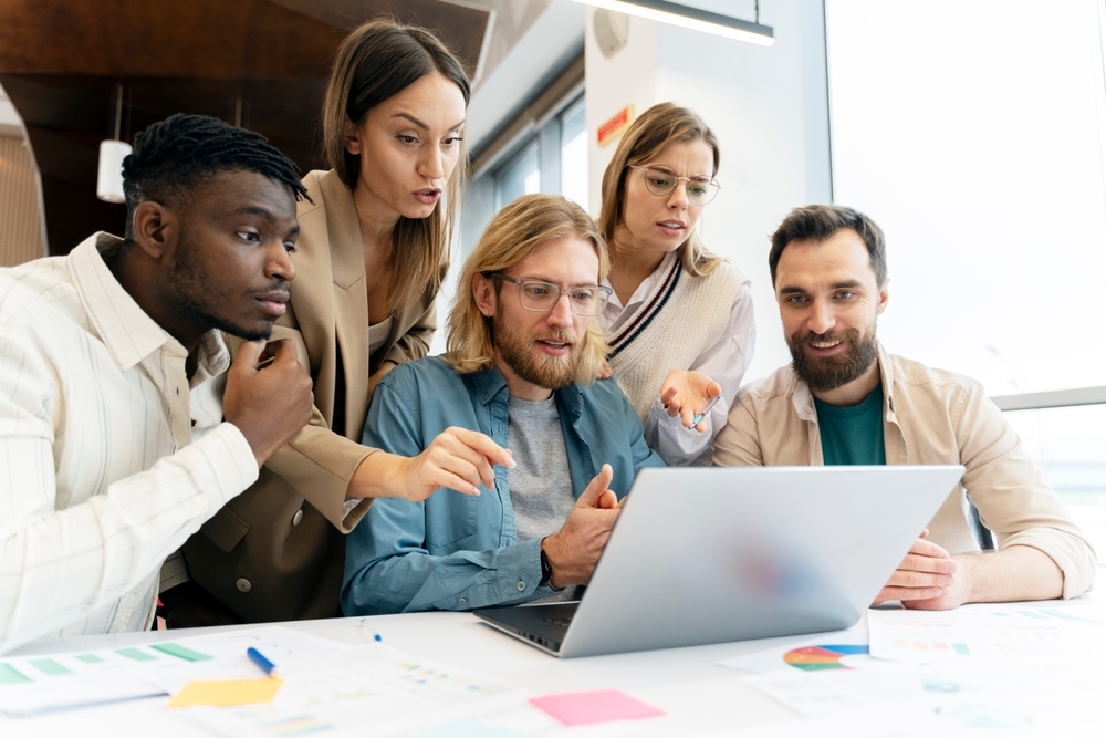 Coaching team gathered around one laptop reviewing member data