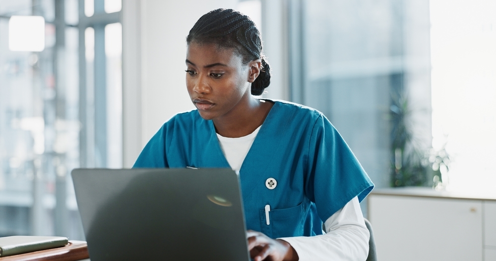 GLP-1 discontinuation coaching care team Nurse in scrubs reviewing patient information on a laptop in a clinic office