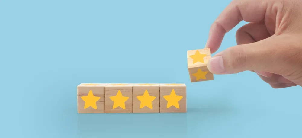 Hand placing a fifth star block beside four wooden star blocks, representing Medicare Star Ratings 2027