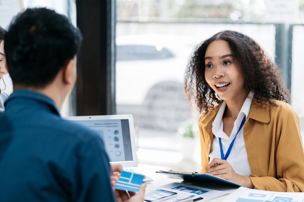 Two people in a meeting reviewing program results across a table