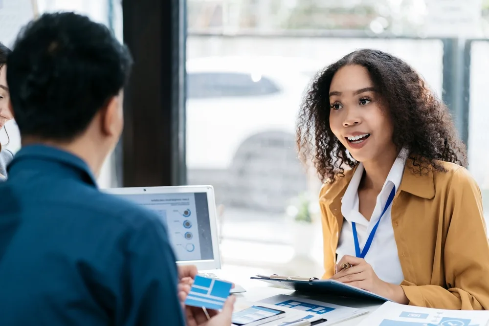Two people in a meeting reviewing program results across a table