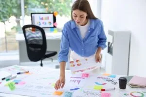 Woman laying out printed charts and sticky notes across a desk to plan a program