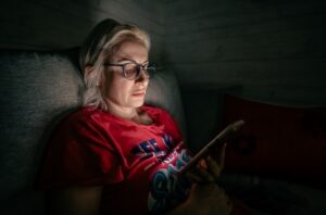 Woman on a couch at night reading a message on her phone