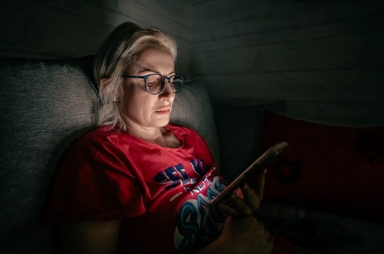 Woman on a couch at night reading a message on her phone