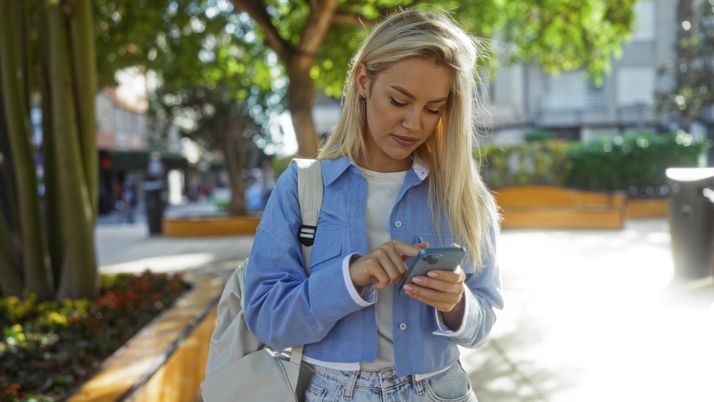 How long should a coaching program run A woman with a backpack checking a message from her health coach on her phone outside