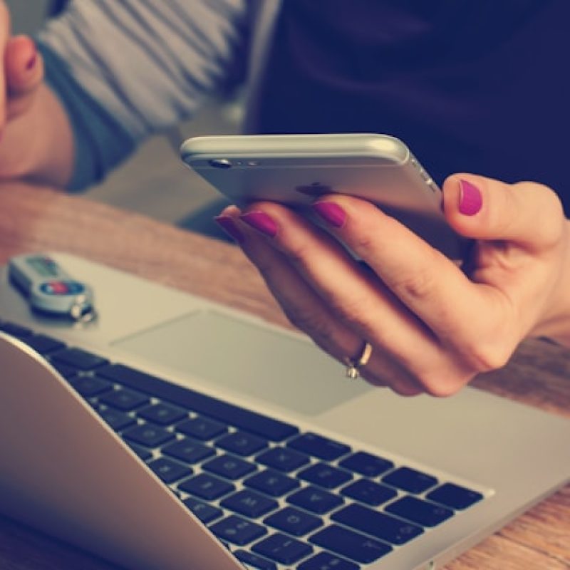 Modern workplace multitasking and the need for smarter wellness strategies Employee multitasking on laptop and phone during the workday, representing the challenge of staff wellness in busy environments.