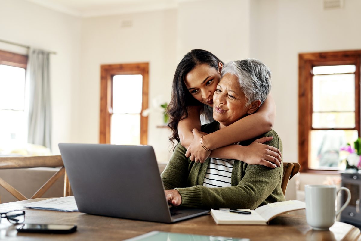 Cropped shot of an attractive young woman hugging her grandmother before helping her with her finances on a laptop