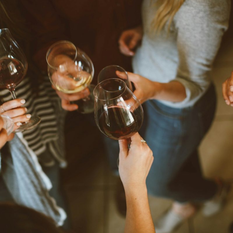 Women holding wine glasses at a social gathering, representing mindful drinking and staying social while working toward drinking less