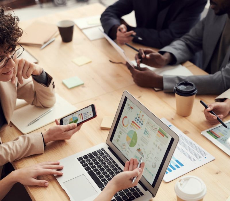 Analyzing Employee Wellness Metrics for Strategic Cost Savings Team of professionals reviewing wellness and cost-saving data on digital devices in a collaborative office setting.