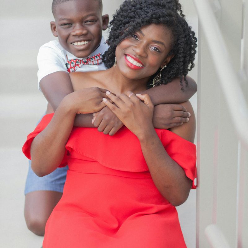 Mother and Son Smiling Together – Raising Healthy Families Series Mother and son smiling and embracing on outdoor steps, representing warmth and connection in a healthy family.