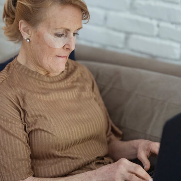 Digital Wellness and Virtual Connection for Senior Residents Older adult woman using a laptop from home, representing virtual engagement and digital wellness tools for senior living residents.